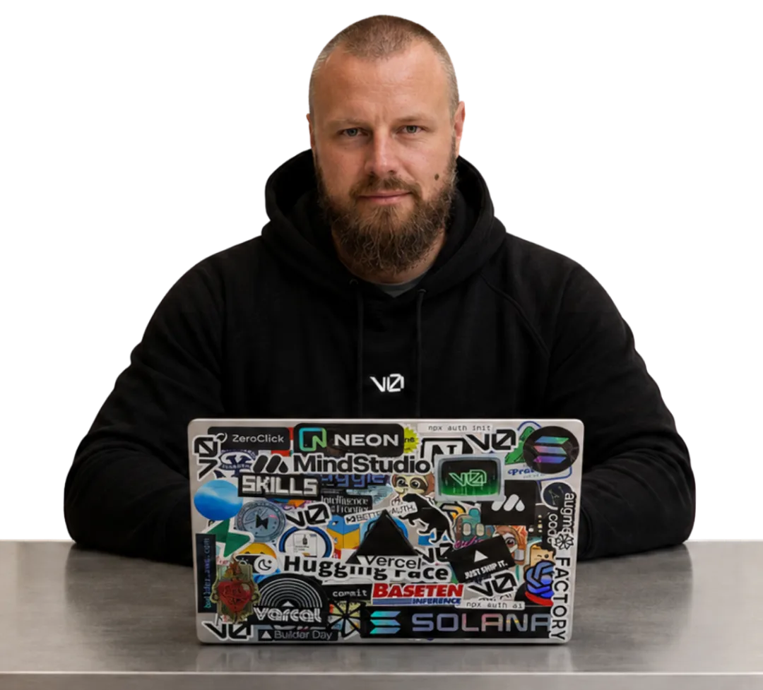 Jon sitting at a steel counter behind an open laptop covered in developer stickers